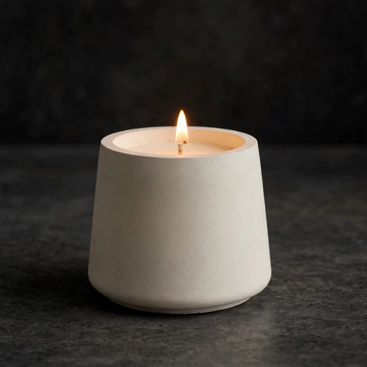Lit soy candle in a white trapezoid concrete vessel